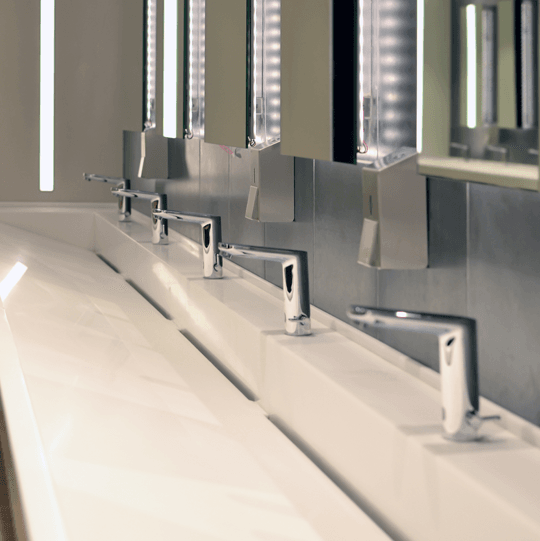 A view of a large sink with several faucets
